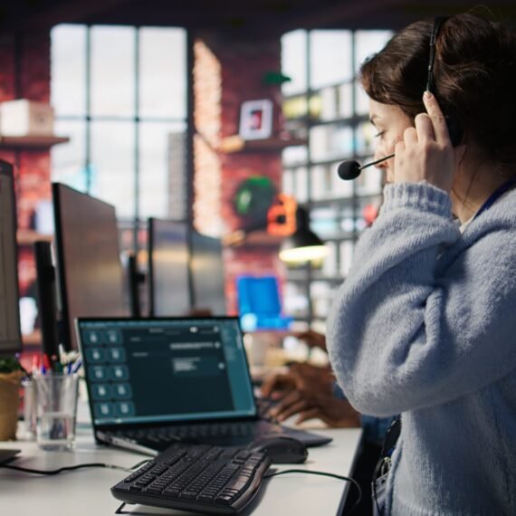 Customer support agent arriving at work, entering office, assisting customers with inquiries. Call center employee sitting down at PC desk, starting account management tasks, camera B